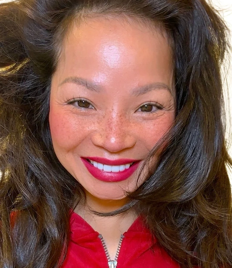 Close-up portrait of Melinda Bui, founder of ME-LIPS, smiling with pink-red lipstick and wearing red